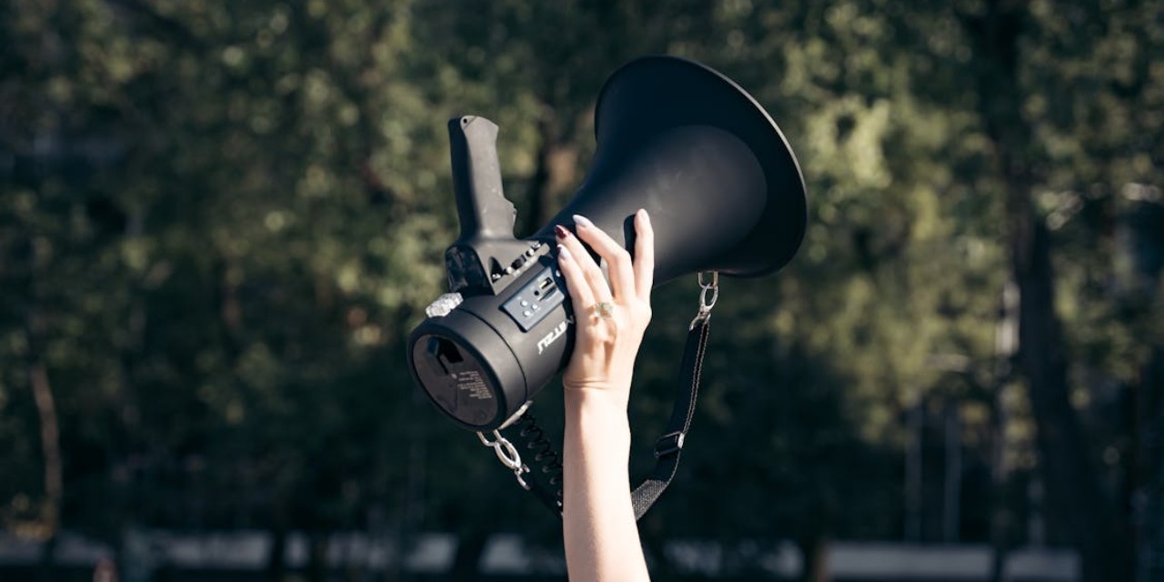 Una mano sujetando un megáfono en alto.